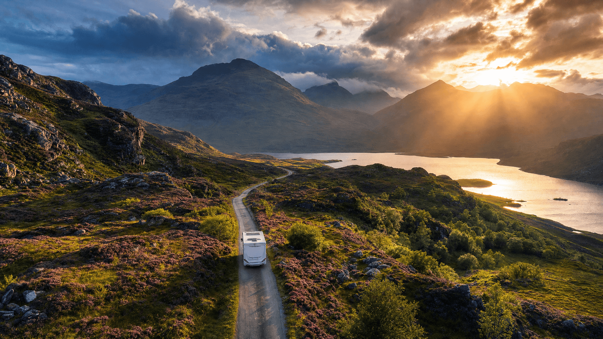 Aerial view of a caravan on a winding road through the Scottish Highlands